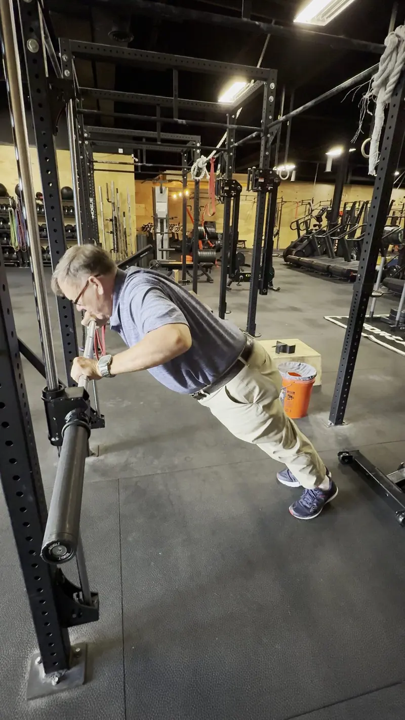 A man pressing dumbbells in a gym