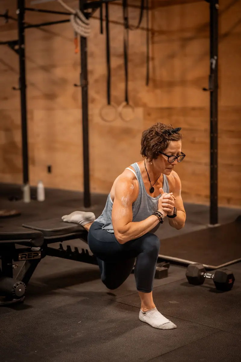 A woman holding a side plank on a gym floor